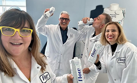 People in white lab coats, with "flow" on the name labels and holding bottles of flow water 