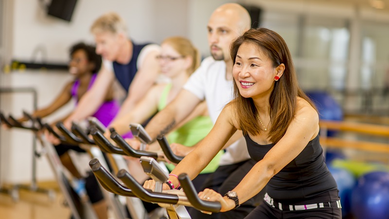 Adult in group fitness class riding on exercise bikes