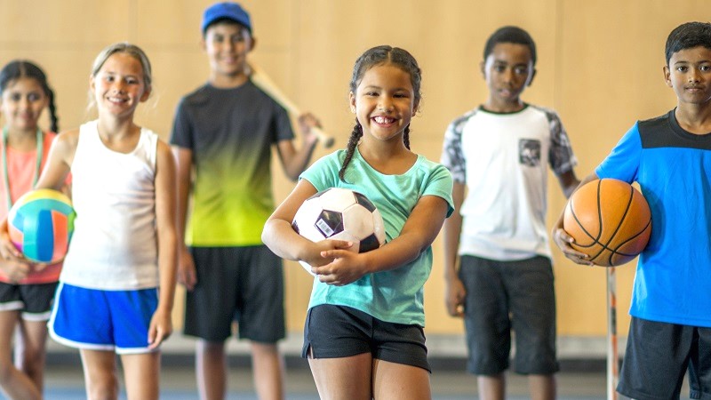 Group of kids in gymnasium holding balls