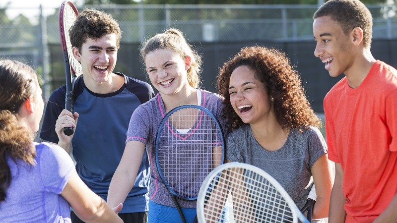 Teenagers playing tennis outdoors