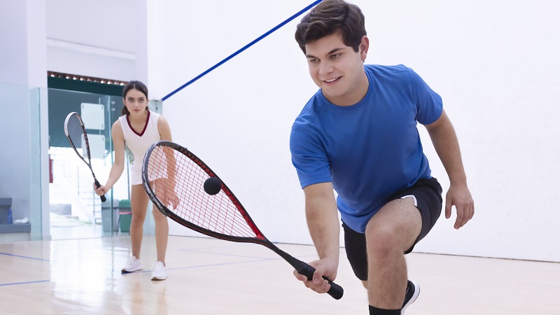 Two young adults playing squash