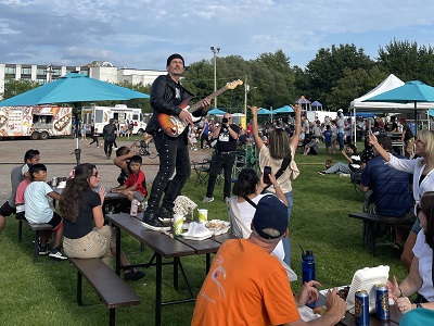 People eating ribs at picnic benches watching music show