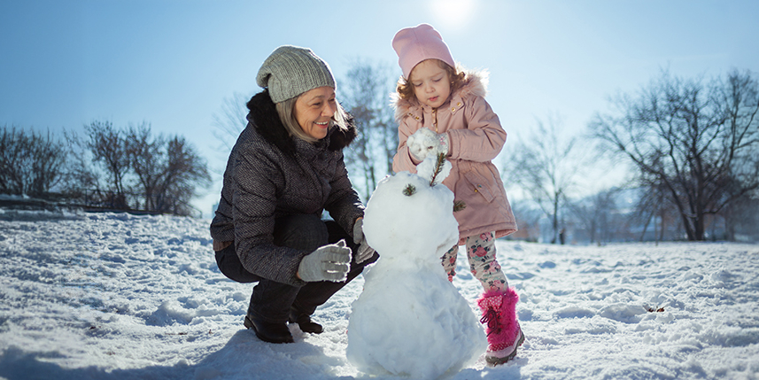 Grandmother and grandchild making snowman