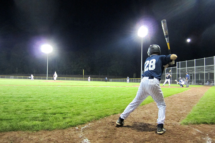 Person playing baseball at night on a field