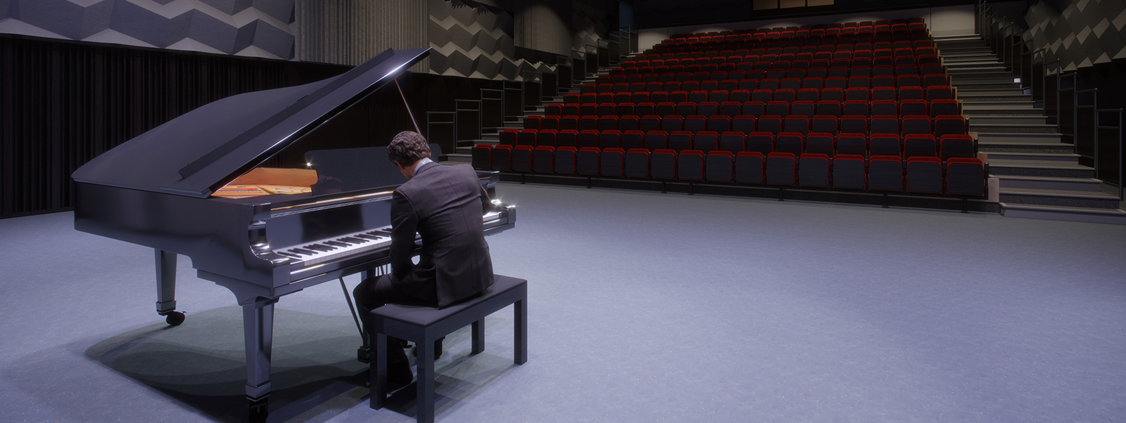 Man playing piano in a dark performance hall, with empty red seats