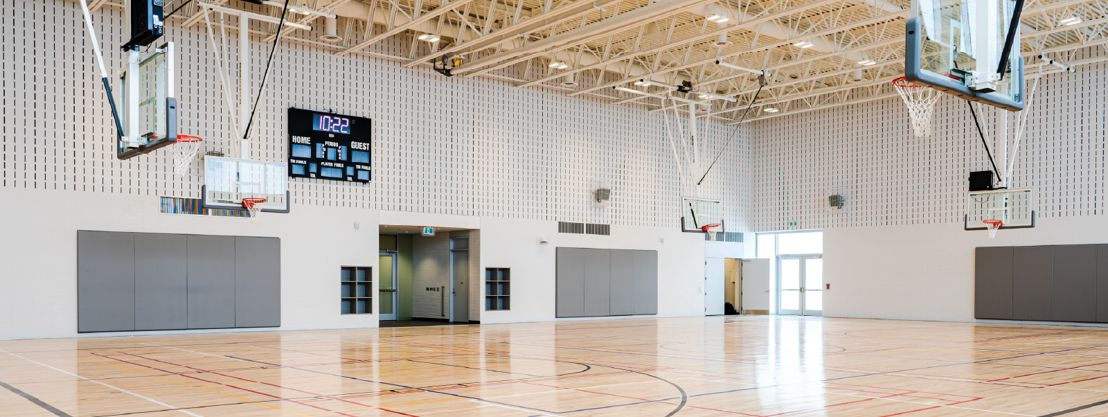 Inside of the new gym, with wood floors, basketball hoops and score board