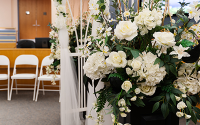 Floral arrangement , with wedding arch and white chairs behind