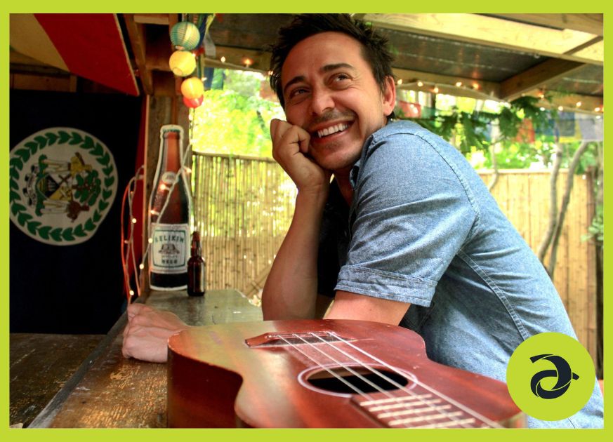 A man sitting at an outdoor bar with his guitar