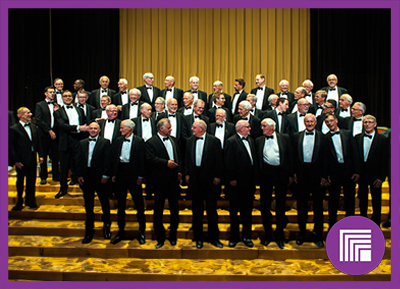 Toronto Welsh Male Voice Choir singers, in black tuxedos, on stage